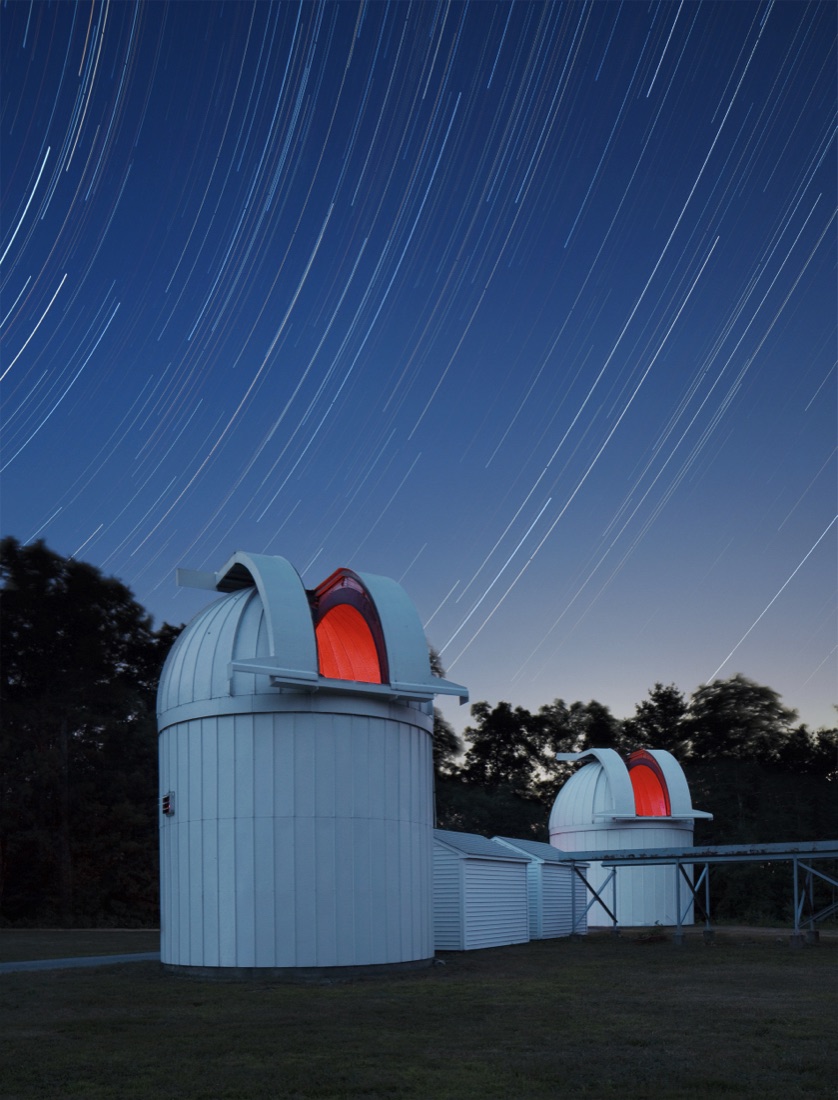 The two domes of the Wallace Astrophysical Observatory at night, lit red under star trails